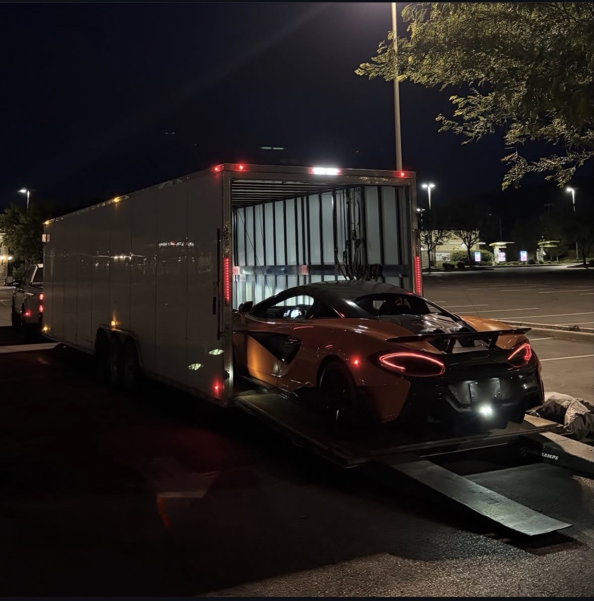 McLaren loaded into a Royalty Auto Transport enclosed trailer at night